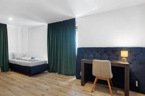 a bedroom with a desk and a bed and a chair at Bergblick Apartments in Radolfzell am Bodensee