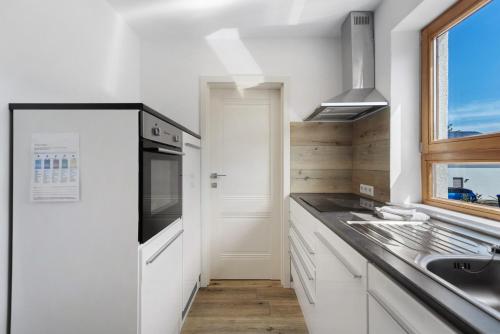 a kitchen with white cabinets and a sink and a window at Bergblick Apartments in Radolfzell am Bodensee