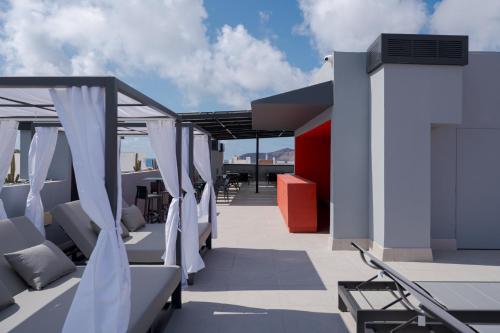 a rooftop patio with chairs and curtains on a roof at Hotel LIVVO La Escarlata in Las Palmas de Gran Canaria