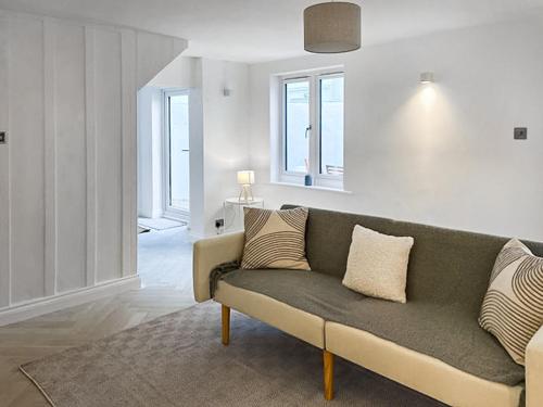 un soggiorno con divano verde e alcune finestre di Samphire Cottage a Cromer