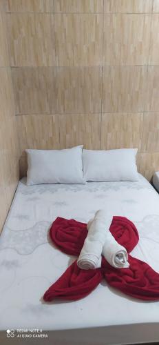 a bed with a red blanket and a towel on it at Pousada Flat do Igor com Ar Condicionado Perto da Basílica de Aparecida com 1 vaga Gratuita no Estacionamento in Aparecida