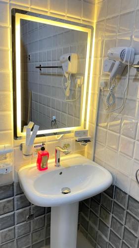 a bathroom with a white sink and a mirror at فندق شركة صلاح المدينة in Az Zāhir