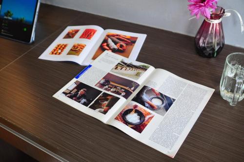a table with two open magazines and a vase with flowers at GRAYHAUS BU4 5BR House - Bandar Utama, near 1 Utama - Stay Only NO EVENTS in Petaling Jaya