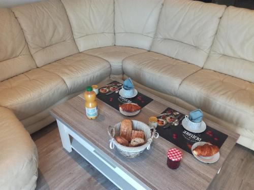 a couch with a coffee table with food on it at Au Fil de l'Eau in Château-Gontier