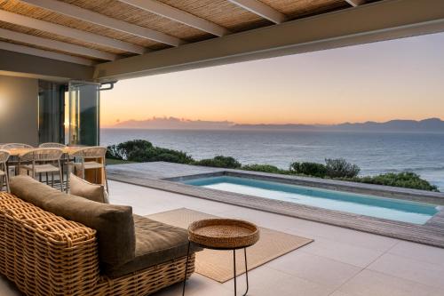 a patio with a swimming pool and the ocean at Romansbaai Collection in Gansbaai