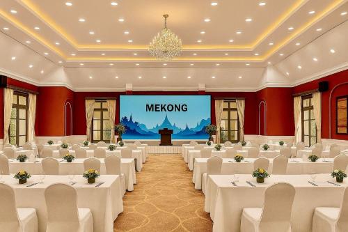 a banquet hall with white tables and a screen with meowing at The Grand Luang Prabang, Affiliated by Meliá in Luang Prabang
