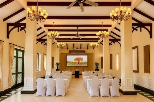 a banquet hall with white chairs and a room with a stage at The Grand Luang Prabang, Affiliated by Meliá in Luang Prabang