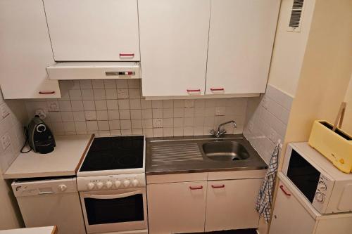 une petite cuisine avec des armoires blanches et un évier dans l'établissement Apartment with balcony just next to ski slope, à La Salle Les Alpes