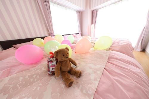 a teddy bear sitting on a bed with balloons at Duetoir 801 / Vacation STAY 7558 in Nagoya