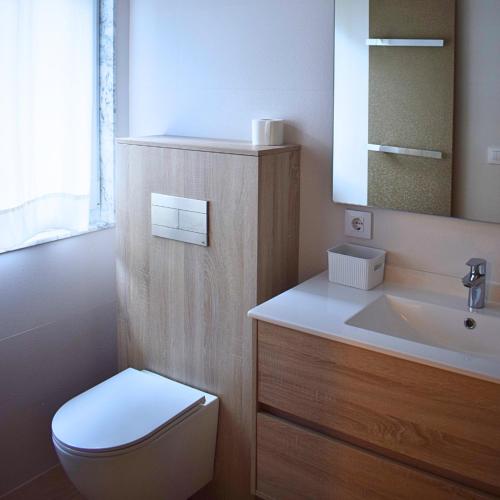 a bathroom with a white toilet and a sink at Villa El Encinar de Noja in Noja