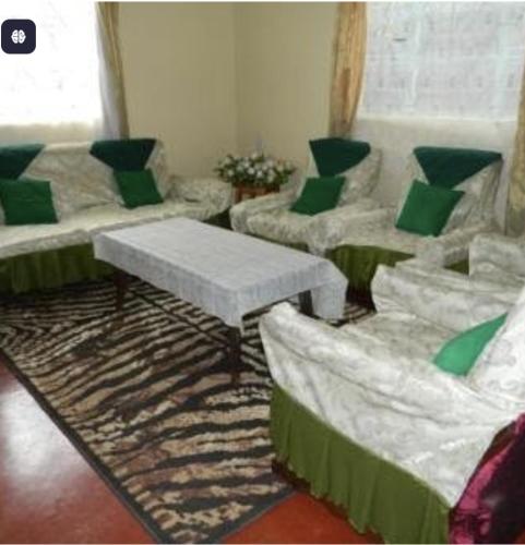 a living room with white couches and green pillows at Glad Homes in Karatina
