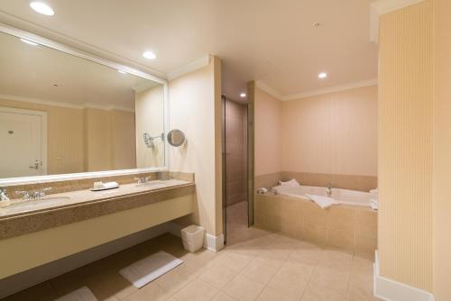 a bathroom with a large mirror and a tub and a sink at The Glen Club in Glenview
