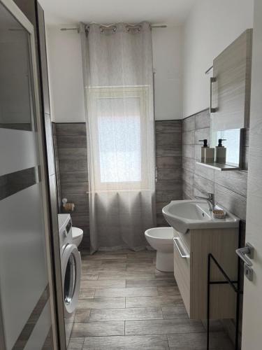 a bathroom with a sink and a toilet and a window at Luxury Green Apartment in Milazzo