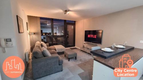 a living room with a couch and a tv at Canal Side Flat by City SuperHost in Manchester