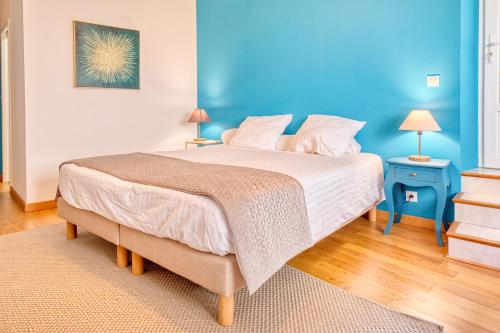 a bedroom with a large bed with a blue wall at Gite L'Envie d'Eymet in Eymet