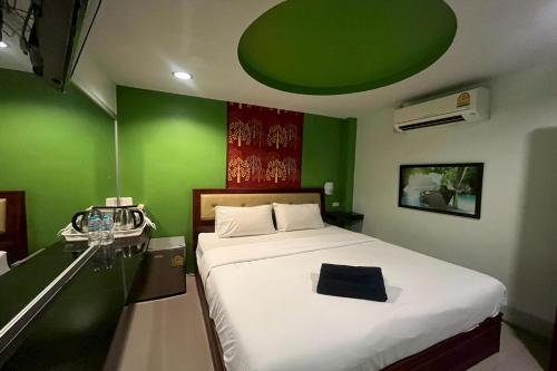 a green bedroom with a bed and a green wall at Krabi Orchid Hometel in Krabi town