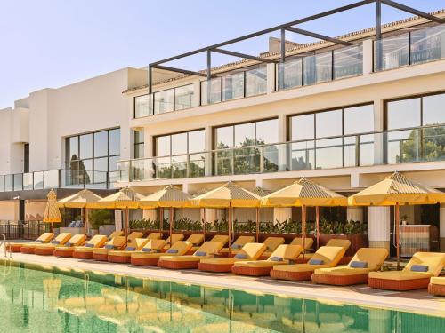 a pool with chairs and umbrellas next to a building at Don Carlos Marbella in Marbella