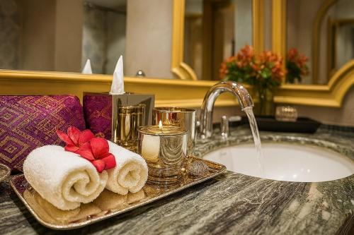 a bathroom sink with towels on a tray next to a sink at The Grand Luang Prabang, Affiliated by Meliá in Luang Prabang