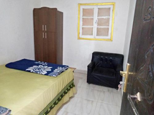 a bedroom with a bed and a chair and a window at Mondy Pyramids Hotel in Cairo