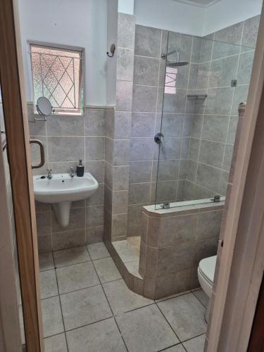 a bathroom with a shower and a sink and a toilet at Ulu Garden Cottage in Ramsgate