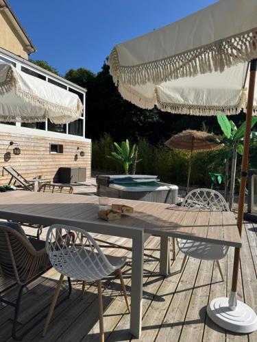 a patio with a table and chairs and an umbrella at Forest Villa in Saint-Clair-de-Halouze