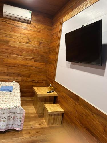 a bedroom with wooden walls and a flat screen tv at Motel tuệ nhi II in Plei Kơtêng