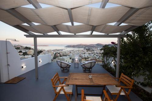 un patio con mesa y sillas y vistas a la ciudad en Stonehill Suites Ano Syros, en Ano Syros