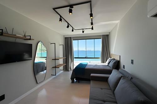 1 dormitorio con sofá, cama y espejo en Loft Refugio Azul - 307, en Arraial do Cabo
