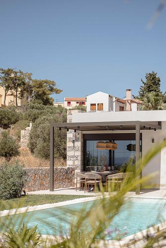 a house with a patio with a table and a pool at Villa Yoma- Luxury Villa with Heated Pool in Epáno Kefalás