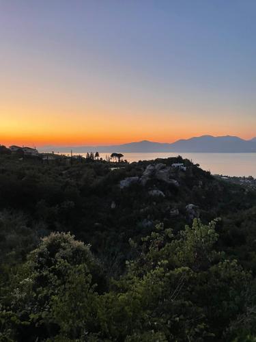 a sunset on a hill with trees and the ocean at Jacob's Place Kalamos in Kalamos