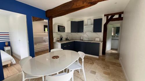 une cuisine et une salle à manger avec une table et des chaises blanches dans l'établissement Gîtes, Les Fontaines de Normandie, à Saint-Julien-sur-Calonne