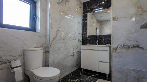 a white bathroom with a toilet and a sink at Cantinho do Azibo 