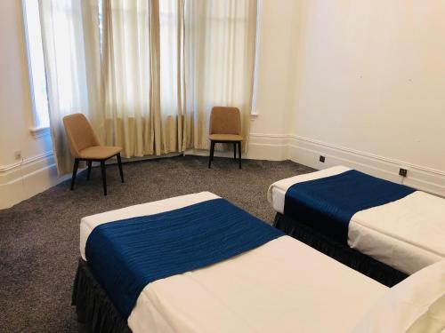 a hotel room with two beds and two chairs at Albany, Brighton & Hove in Brighton & Hove