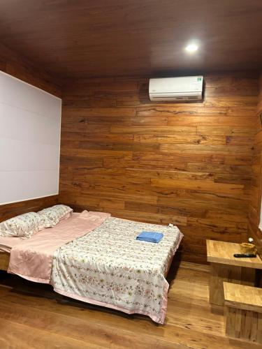 a bedroom with a bed and a fan and wooden walls at Motel Tuệ Nhi II in Plei Kơtêng