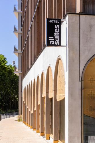 a hotel with a sign on the side of a building at All Suites Hôtel - Paris Pleyel - L'Île Saint Denis in LʼÎle-Saint-Denis