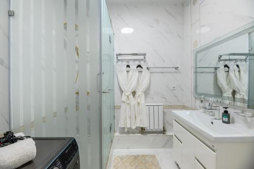 a white bathroom with a sink and a mirror at Большая трехкомнатная, с видом на горы in Zhezdi