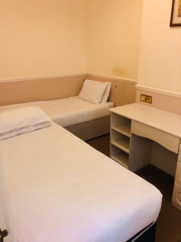 a small room with two beds and a desk at Albany, Brighton & Hove in Brighton & Hove
