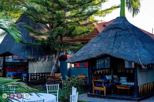 a hut with a thatched roof and a table and chairs at Twalumba Lodge in Lusaka