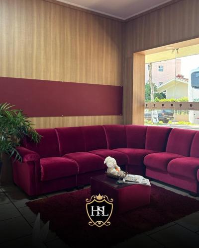 a living room with a red couch and a table at Hotel São Luiz Iraí in Iraí