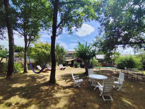 a picnic table and chairs in a yard with trees at La Maison des Forges, ancienne grange charentaise transformée en habitation atypique en lisière de forêt pour 10 personnes maximum in Cellefrouin