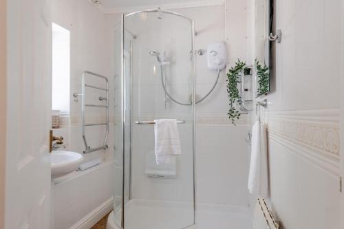 a white bathroom with a shower and a sink at Woodstock in Ventnor