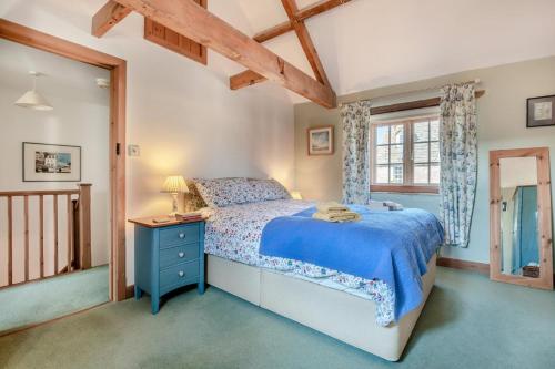 a bedroom with a blue bed and a window at Alice Cottage - Corfe Castle in Corfe Castle