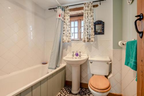 a bathroom with a toilet and a sink and a tub at Alice Cottage - Corfe Castle in Corfe Castle