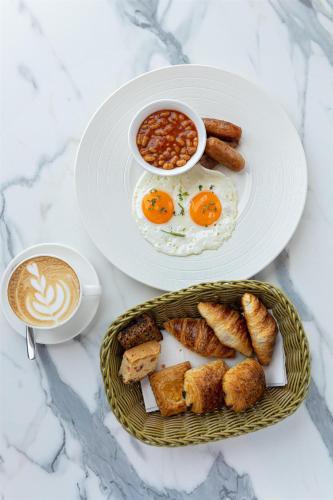 two plates of breakfast foods with a cup of coffee at Levatio Suites Muscat, a member of Radisson Individuals in Muscat