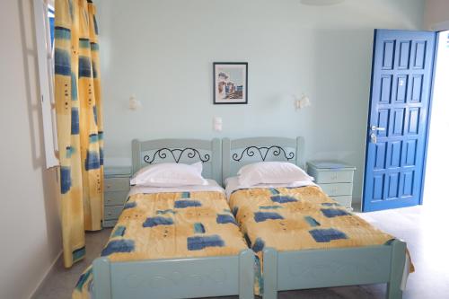 two beds in a bedroom with blue doors at Maroussa Studios in Agia Anna Naxos