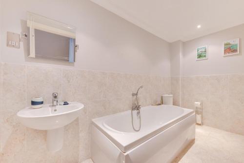 a bathroom with a white tub and a sink at Flat 1 Deco in Swanage