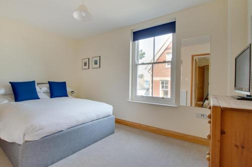a bedroom with a bed with blue pillows and a window at Flat 4 Penlu in Swanage