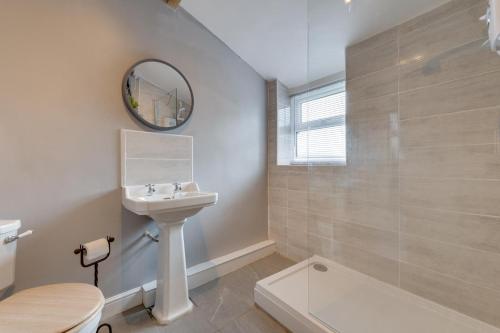 un bagno con lavandino, WC e specchio di Beau Cottage a Crich