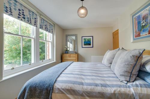 a bedroom with a bed and two windows at Flat 5 Penlu in Swanage