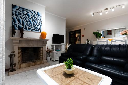 a living room with a black leather couch and a fireplace at Blue Bay Apt - São Martinho do Porto in São Martinho do Porto